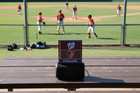 FieldFire Mini single-panel scoreboard on a portable speaker at a community baseball field, showing pregame team logos.
