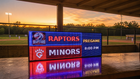 FieldFire Standard three-panel LED matrix scoreboard beneath a protected scorer's canopy at sunset.